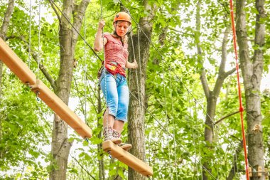 Parkta güzel bir kız, iplerin üzerinde. Açık havada başarıyor.