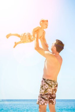 Deniz arka planda oynayan çocuk ile mutlu ebeveyn