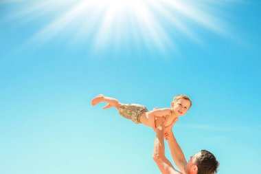 Deniz arka planda oynayan çocuk ile mutlu ebeveyn