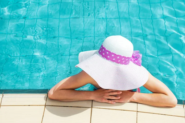 Gelukkig meisje in een hoed bij het zwembad op zee — Stockfoto