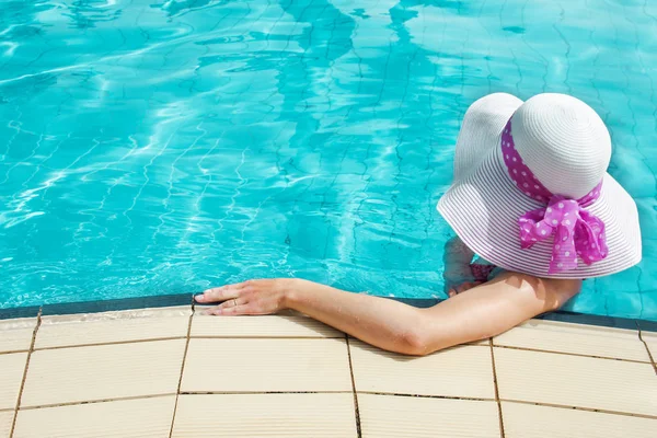 Gelukkig meisje in een hoed bij het zwembad op zee — Stockfoto