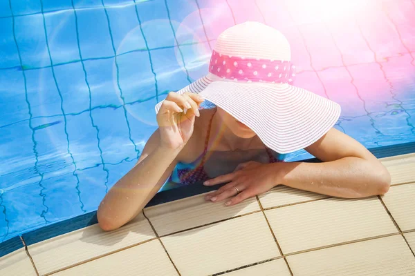 Gelukkig meisje in een hoed bij het zwembad op zee — Stockfoto