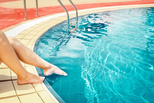 Belle gambe di una ragazza vicino a una piscina sul retro del mare — Foto Stock