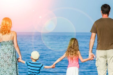 Deniz arka planda oynayan çocuklu mutlu ebeveynler