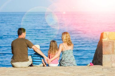 Deniz arka planda oynayan çocuklu mutlu ebeveynler