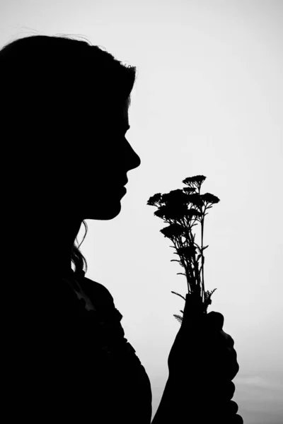 Happy girl with a bouquet silhouette on nature in the park sunse — Stock Photo, Image