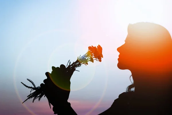 Happy girl with a bouquet silhouette on nature in the park sunse — Stock Photo, Image