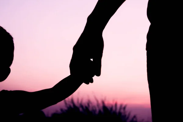 Felice padre genitore con bambino silhouette mano al tramonto in natur — Foto Stock