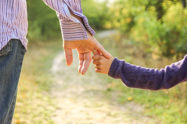 Il genitore che tiene la mano del bambino con uno sfondo felice — Foto Stock