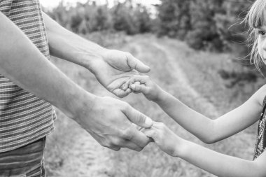 Bir parkta doğada bir ebeveyn ve çocuğun şık elleri geri