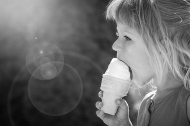 Parkın doğasında dondurma yiyen mutlu çocuk.
