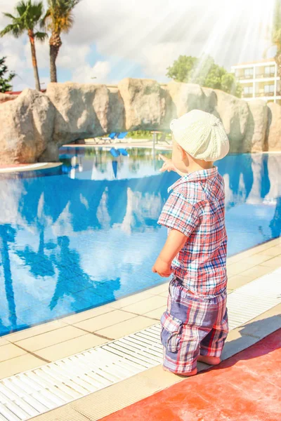 Ett lyckligt barn leker vid poolen på naturen vid havet — Stockfoto