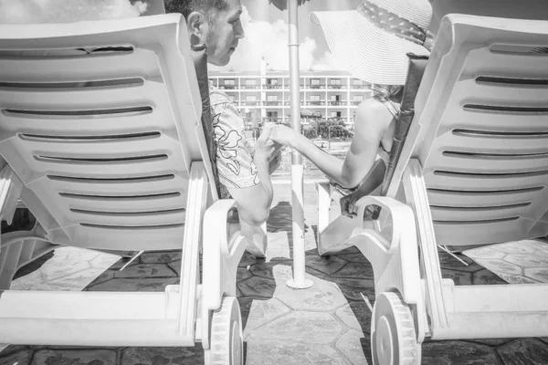 Happy couple in loungers by the pool by the sea — ストック写真