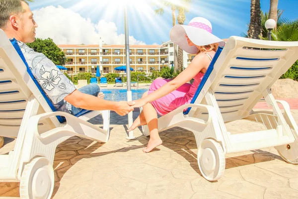 Gelukkig paar in ligstoelen bij het zwembad aan zee — Stockfoto