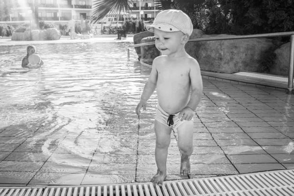 Un niño feliz juega junto a la piscina junto al mar — Foto de Stock