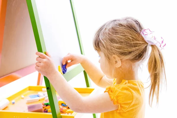 Felice bambina bella pittura sul cavalletto su uno schienale bianco — Foto Stock