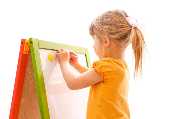 Felice bambina bella pittura sul cavalletto su uno schienale bianco — Foto Stock