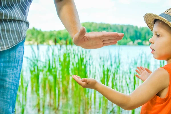 Manos de un padre y un niño en la naturaleza en un parque junto al mar — Foto de Stock