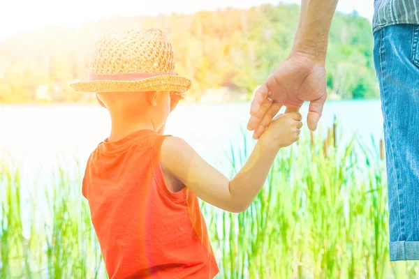 Manos de un padre y un niño en la naturaleza en un parque junto al mar —  Fotos de Stock