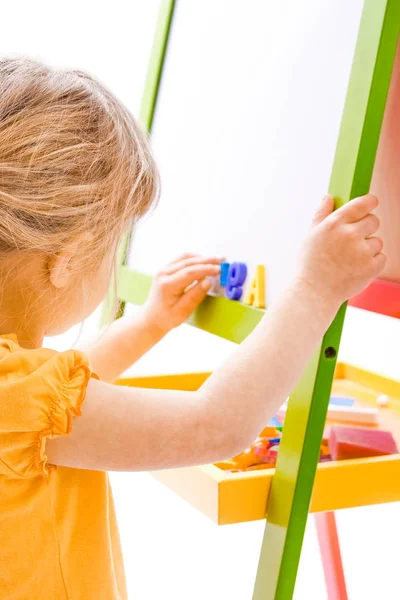 Happy baby girl beautiful painting on the easel on a white backg — Stock Photo, Image