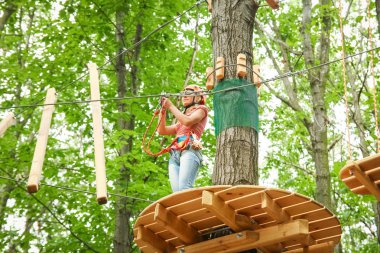 Parkta güzel bir kız, iplerin üzerinde. Açık havada başarıyor.