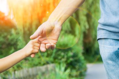 Mutlu bir geçmişi olan çocuğun elini tutan ebeveyn.