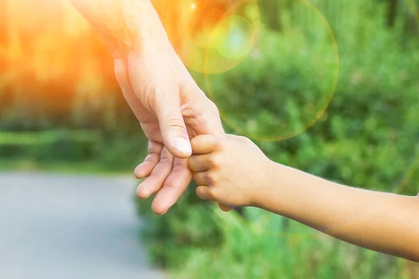 Il genitore che tiene la mano del bambino con uno sfondo felice — Foto Stock