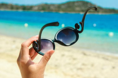 Doğa arka planda deniz güneş gözlüğü ile güzel eller