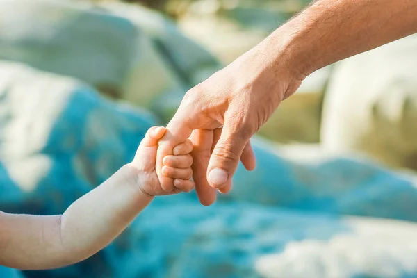 Mooie handen van ouder en kind aan zee — Stockfoto