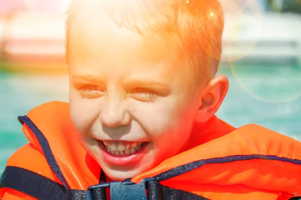 Enfant heureux dans un gilet à la mer jouer — Photo