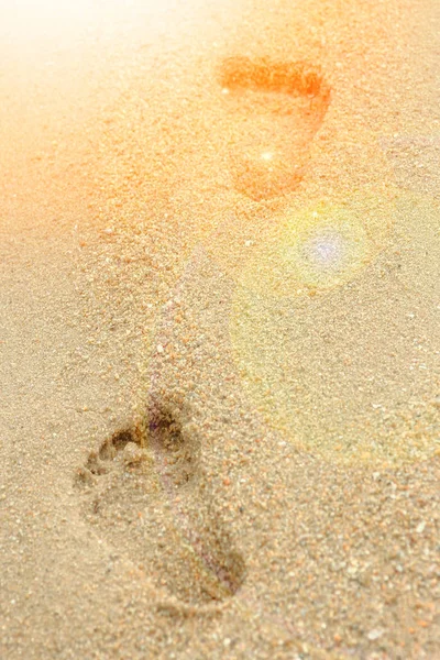 Gyönyörű lábnyomok a homokban a tenger háttere mellett — Stock Fotó