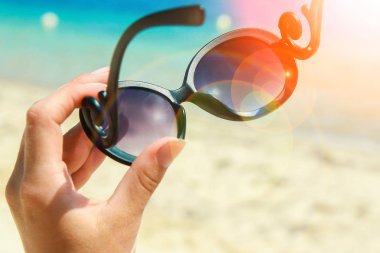 Doğa arka planda deniz güneş gözlüğü ile güzel eller