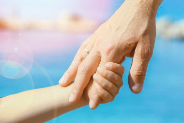 Deniz kenarındaki anne ve babanın güzel elleri.