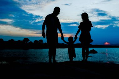 Deniz kenarında mutlu bir aile, doğanın siluetinde.