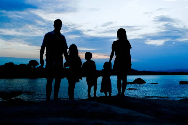 Deniz kenarında mutlu bir aile, doğanın siluetinde. — Stok fotoğraf