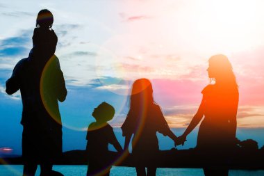 Deniz kenarında mutlu bir aile, doğanın siluetinde.