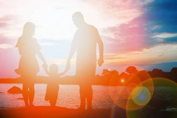 Familia feliz junto al mar en la silueta de la naturaleza de fondo —  Fotos de Stock