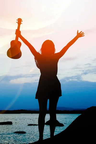 Heureuse fille avec ukulele par la mer sur la nature silhouette backgrou — Photo