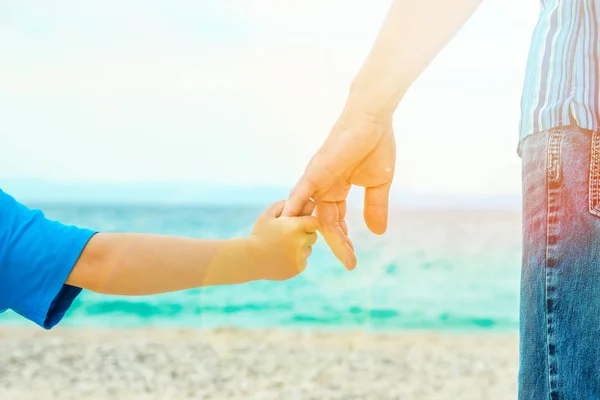 Mooie handen van een gelukkige ouder en kind door de zee in de natuur — Stockfoto