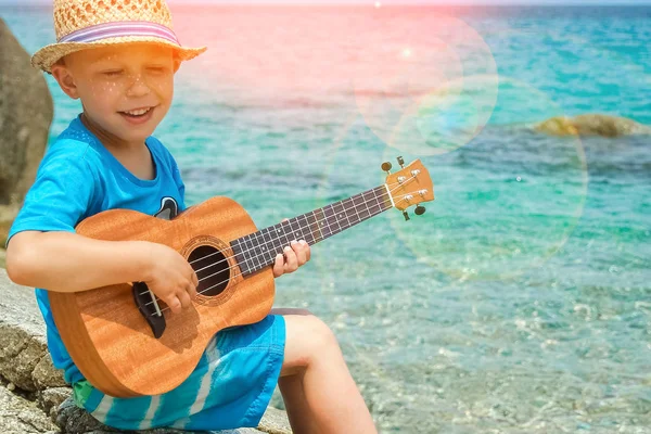 Niño feliz tocando la guitarra por el mar griego en la naturaleza backgroun — Foto de Stock