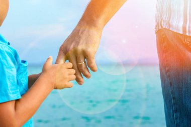hands of happy parent and child at sea greece background clipart