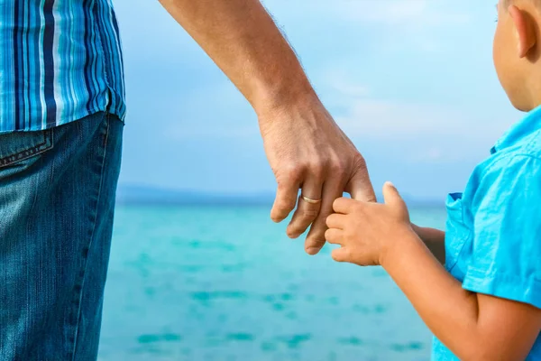 Mani di genitore felice e bambino in mare sfondo greco — Foto Stock