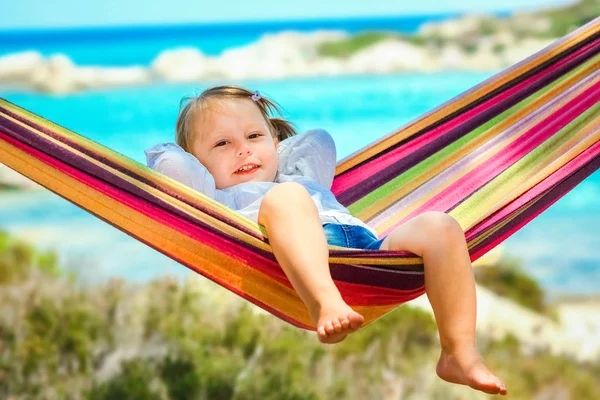 Счастливое дитя у моря на гамаке на греческом фоне — стоковое фото