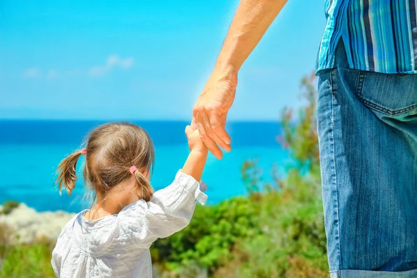 Руки счастливого родителя и ребенка на фоне морской Греции — стоковое фото