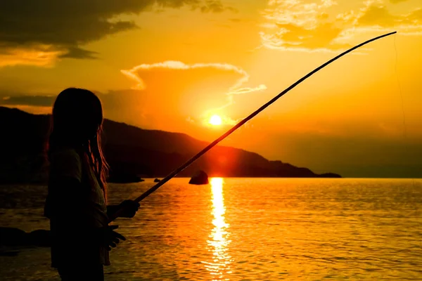 Gelukkig kind vissen door de zee silhouet — Stockfoto