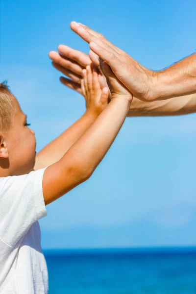 Счастливый папа держит за руку ребенка у греческого моря в природе — стоковое фото