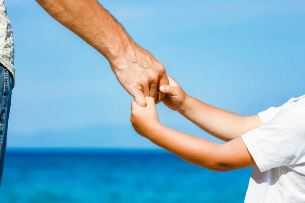Felice papà tiene la mano di un bambino in riva al mare greco in natura — Foto Stock