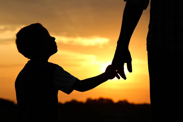 Silueta padre sostiene la mano de un niño —  Fotos de Stock