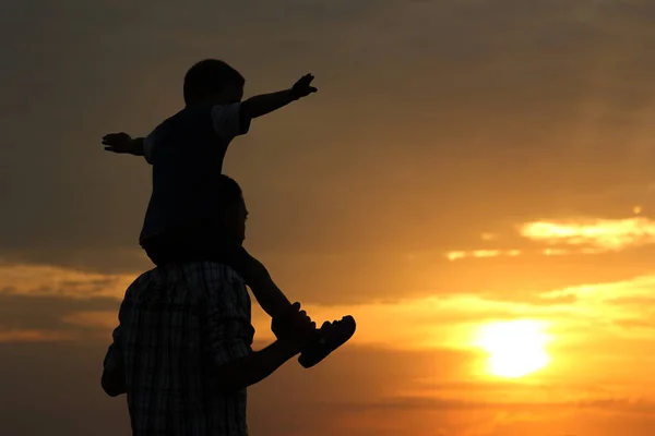 Силует батька і сина на заході сонця — стокове фото
