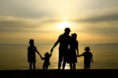 deniz tarafından gün batımında aile silueti